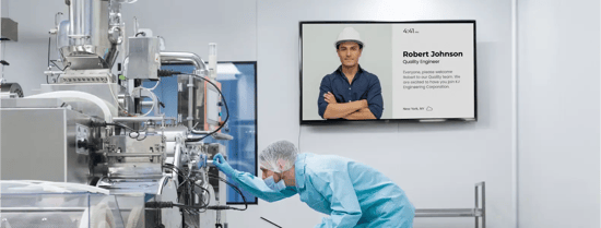 A worker in a manufacturing facility views an employee appreciation message on a digital signage display