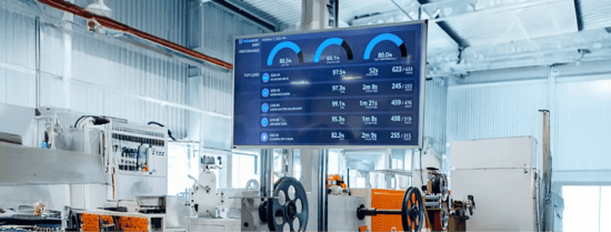 A worker in a manufacturing unit with digital signage displaying production data in the background