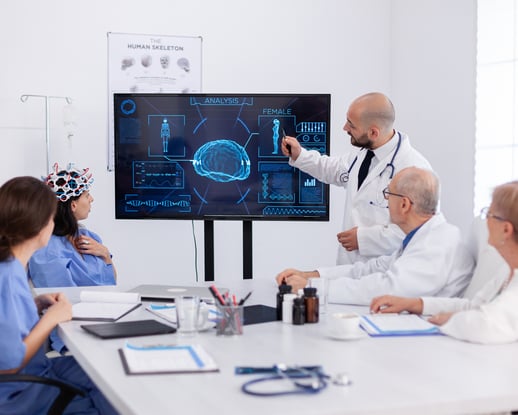 Doctor presenting medical imaging on a digital screen to a team of healthcare professionals in a hospital meeting room